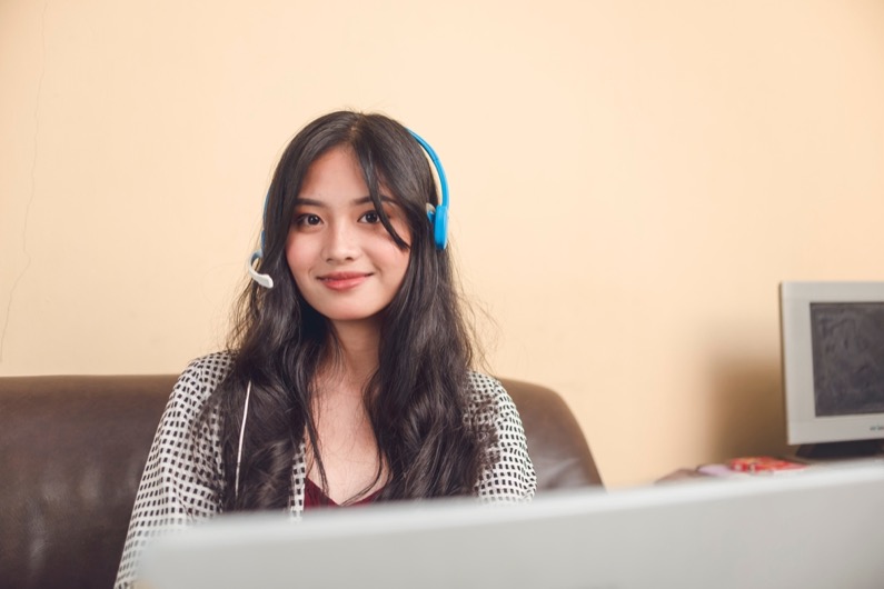 A young and attractive Filipina online teacher working at her living room.