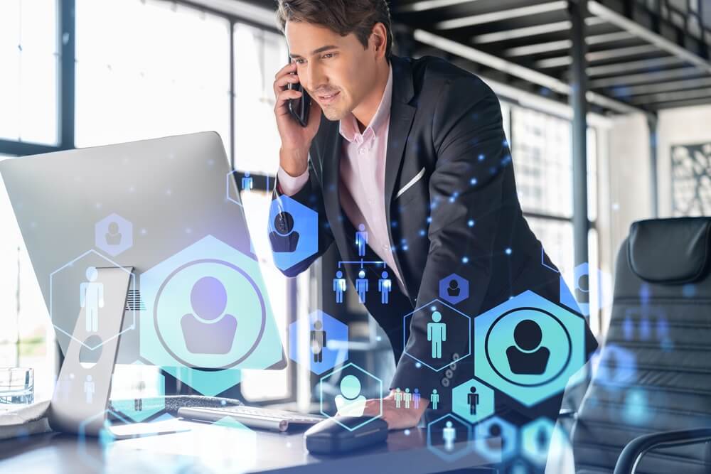 Businessman in suit has conference call to hire new employees for international business consulting. HR, social media hologram icons and interconnections over office background with panoramic windows
