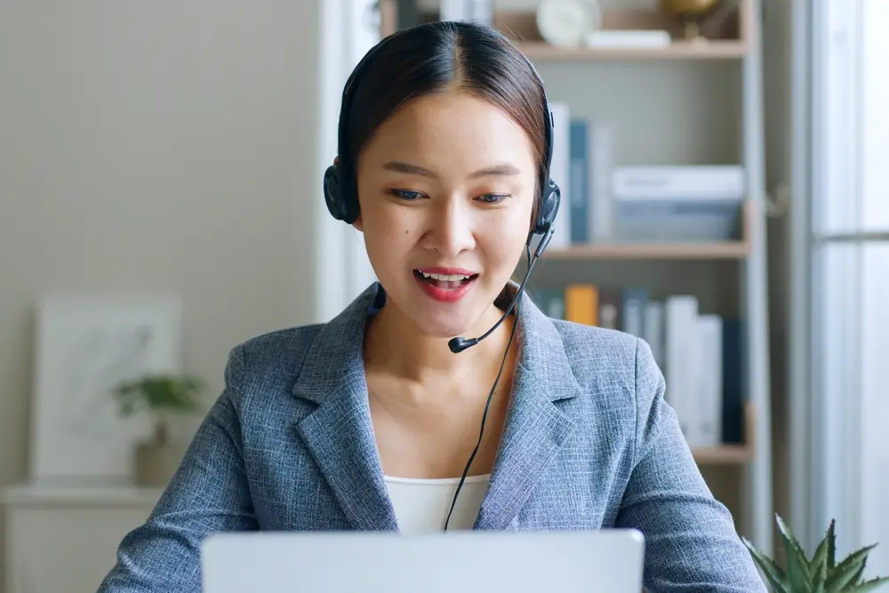 Young Asian businesswoman wearing headphone, call center, customer service talking on video call conference or virtual meeting in office