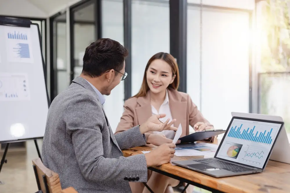 Businesswoman and businessman with laptop and analyzing a chart working together in the office.
