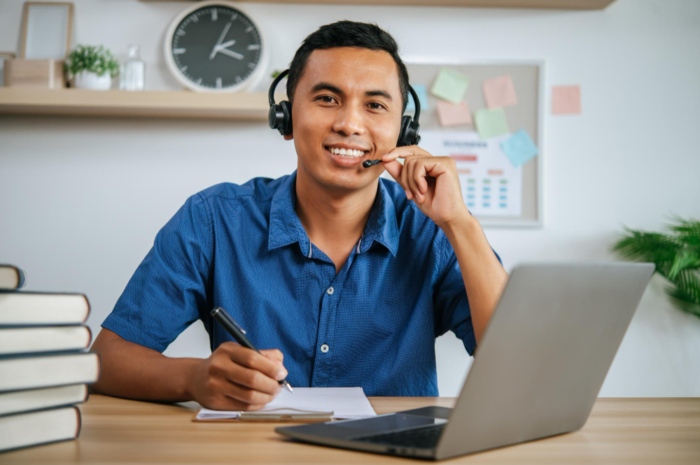 Man with headphones working in office with papers and laptop on desk