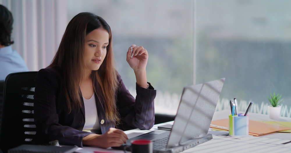 Focused gen z female Assistant worker working on computer typing online email