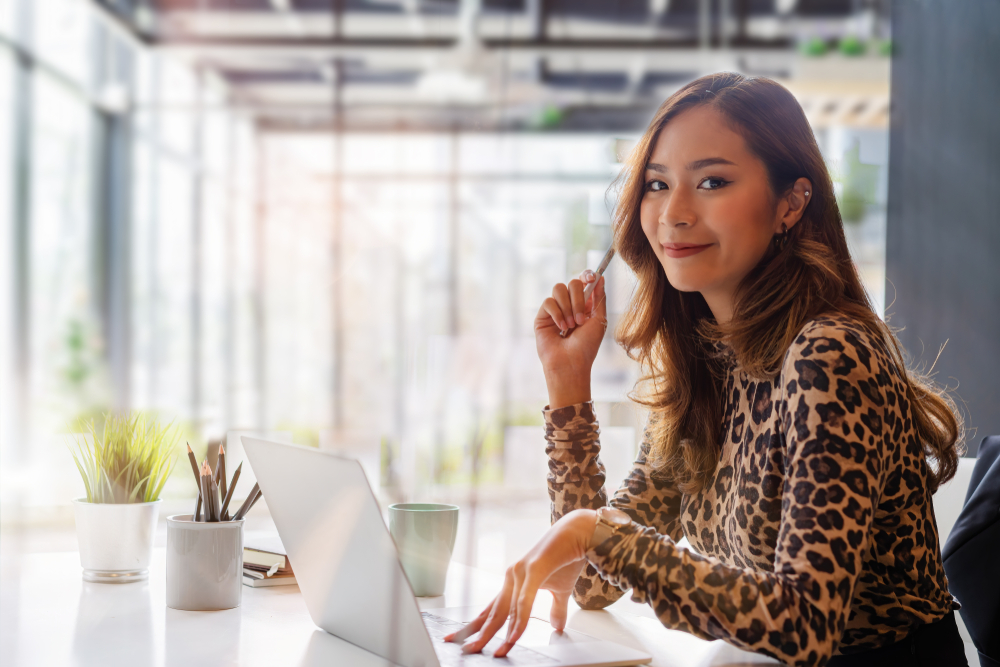 Confident asian businesswoman smiling and look at camera while working on laptop at modern office.