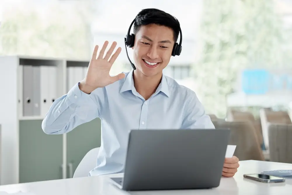 Asian man, laptop and video call in call center, customer service or virtual assistant at the office.