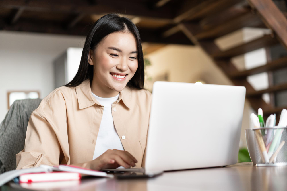 Smiling asian girl waching webinar having work