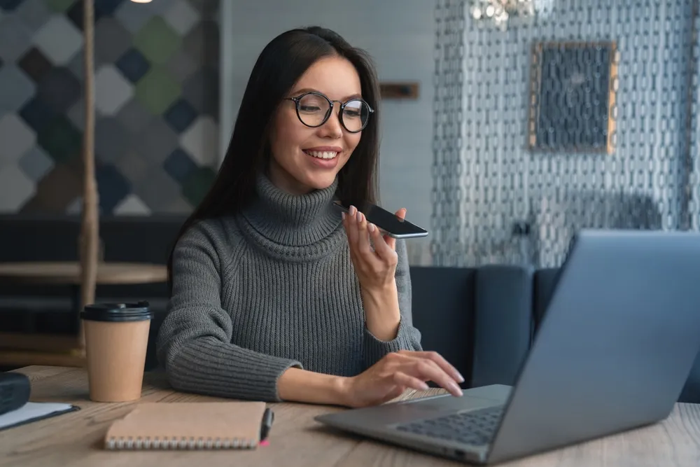 Asian female sitting at office having telephonic conversation and smiling