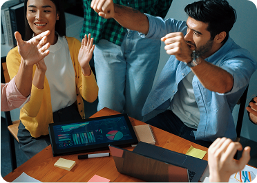 Several individuals seated at a table, enthusiastically raising their hands, indicating participation in a group activity.