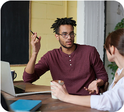 A man and a woman at a table, both looking at the laptop