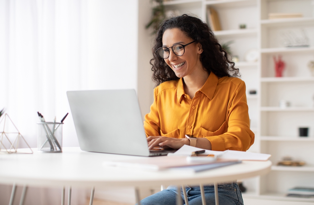 A virtual assistant smiling while working on her laptop