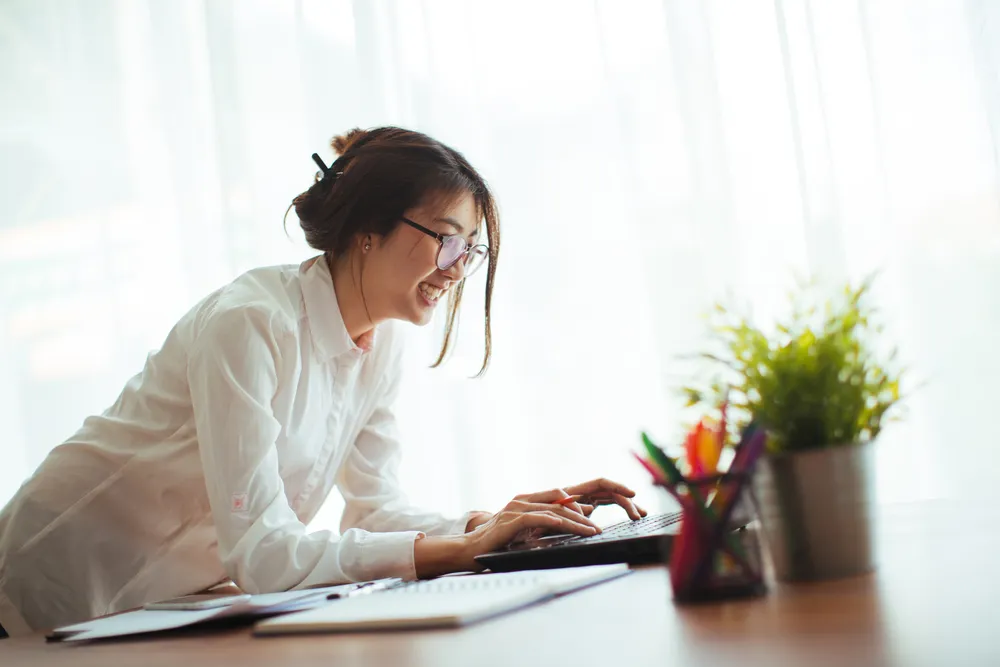 happy young cheerful business woman at home office working on laptop