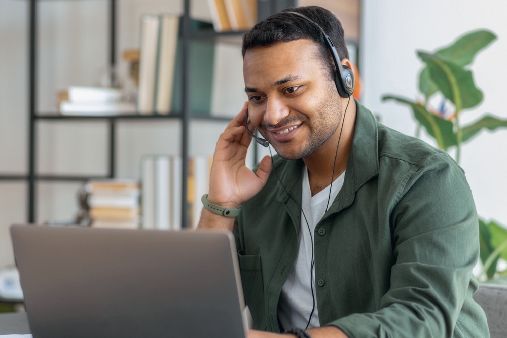 Man entrepreneur works with laptop and headset sitting in the home office