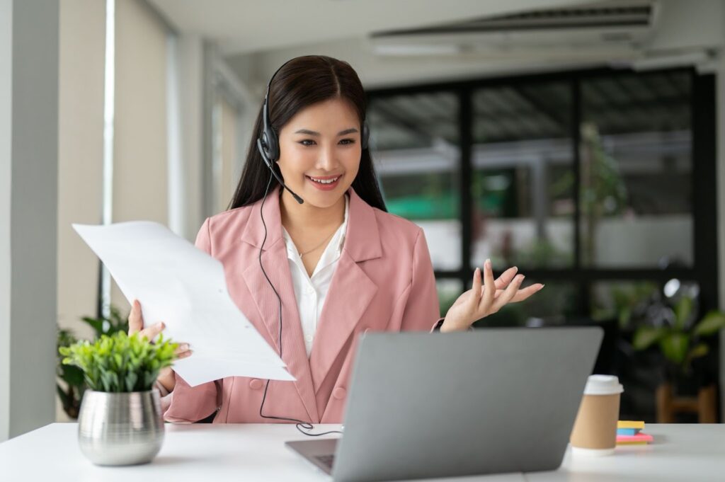 A Customer Service Virtual Assistant in pink suit in front of her laptop