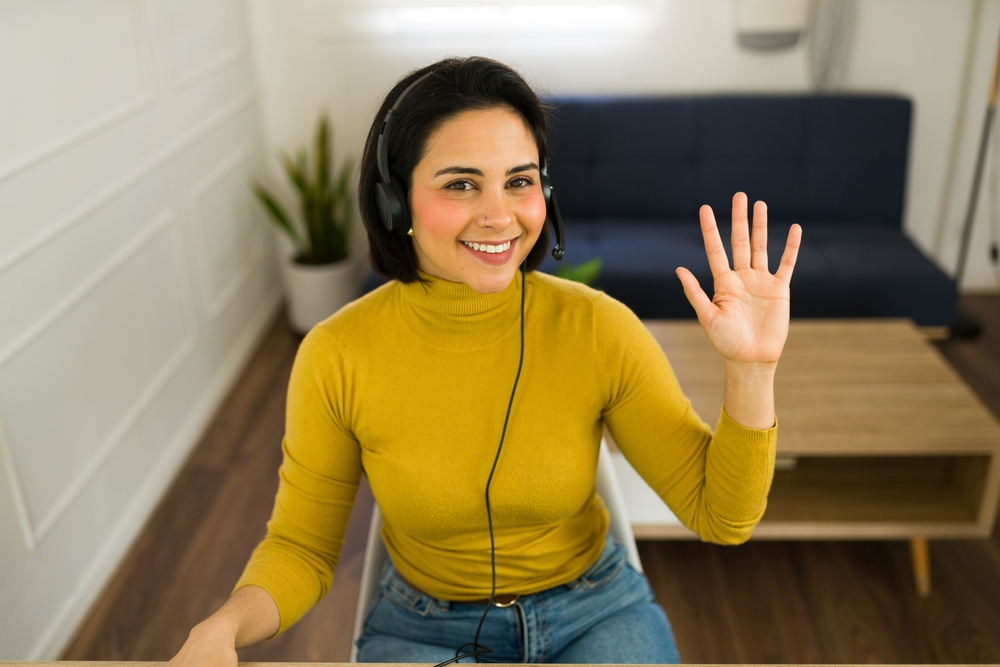 Woman wearing headset, gesturing while working remotely as virtual assistant from home workspace