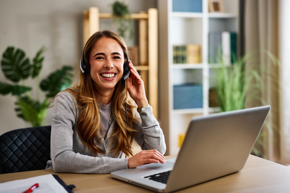 Happy female VA wearing headset and working remotely from home