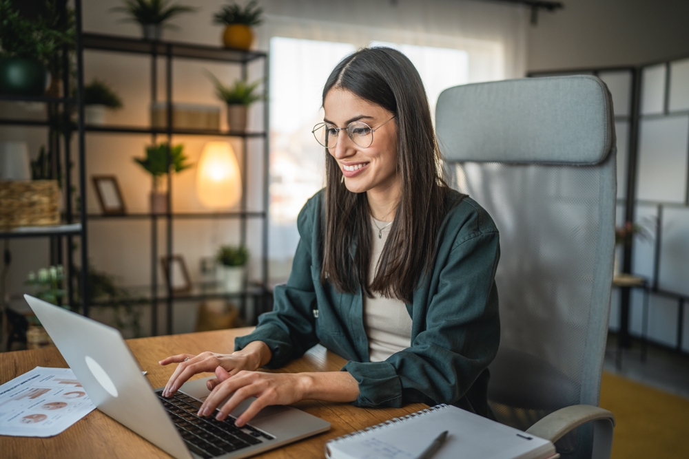 Adult woman work on laptop and use notebook from home office