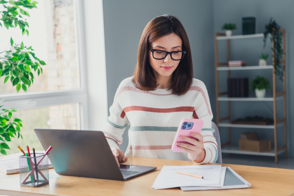 Portrait of pretty ceo assistant girl sit chair use smart phone laptop communicate colleagues workplace office indoors