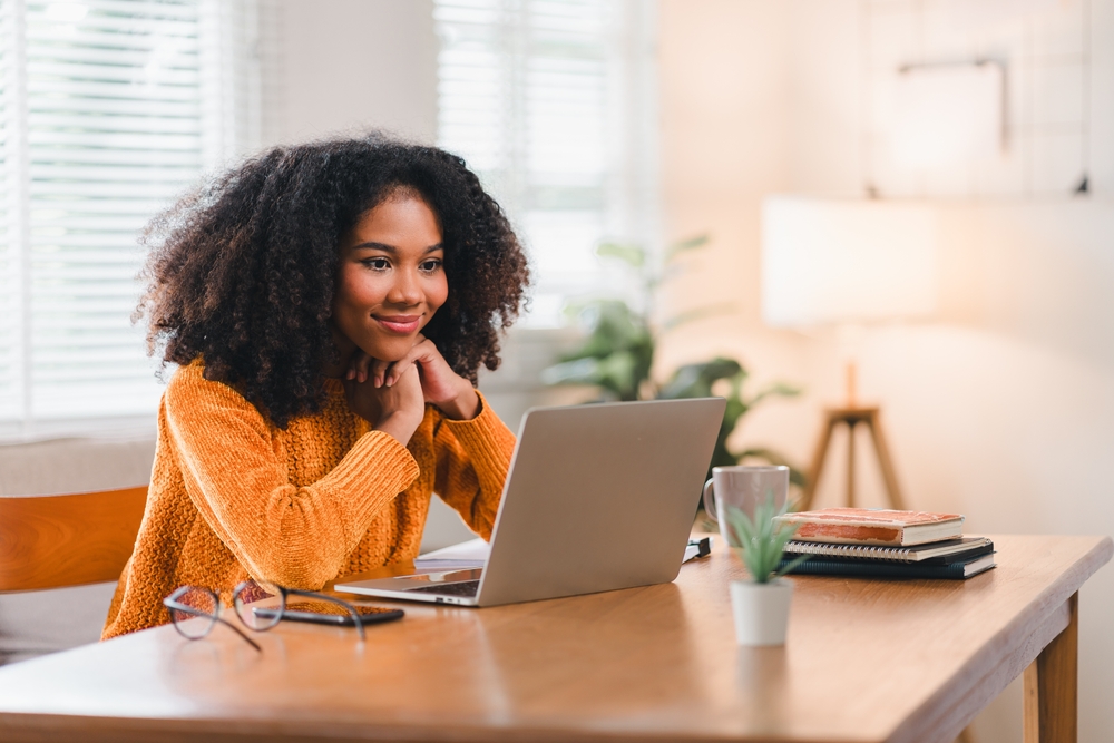 African American woman smiles while watching laptop screen at home