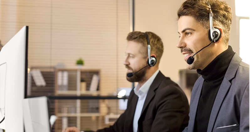 Men agents with headsets provide support. At office computers in a busy callcenter, operators assist a customer and monitor data to deliver consistent service. Lean B2B support concept now.