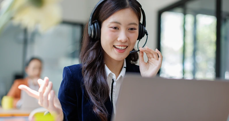 Smiling Customer Support Agent Wearing Headset Working on Laptop in Office