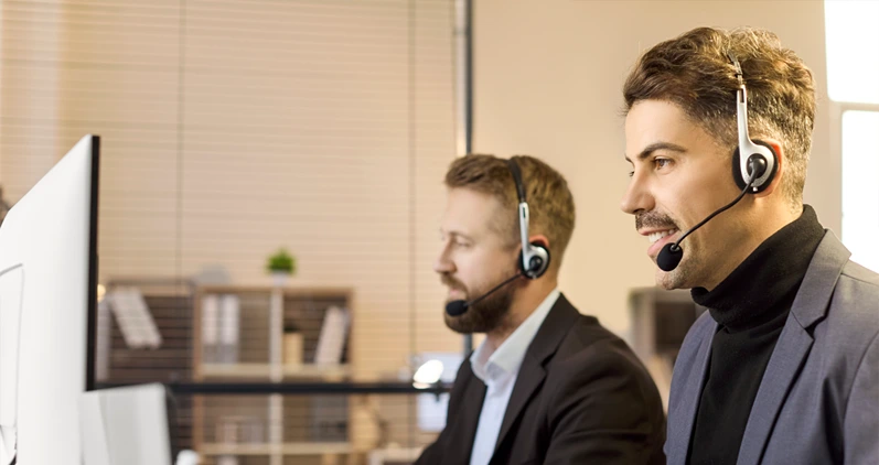 Men agents with headsets provide support. At office computers in a busy callcenter, operators assist a customer and monitor data to deliver consistent service. Lean B2B support concept now.