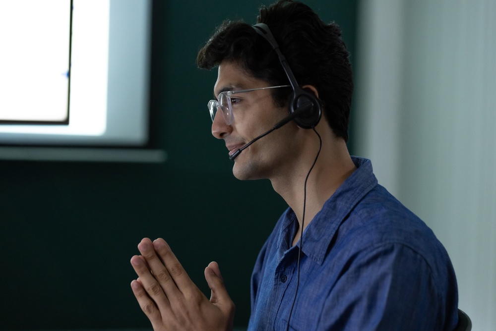 Indian male customer service agent wearing a headset while speaking with a client in an office