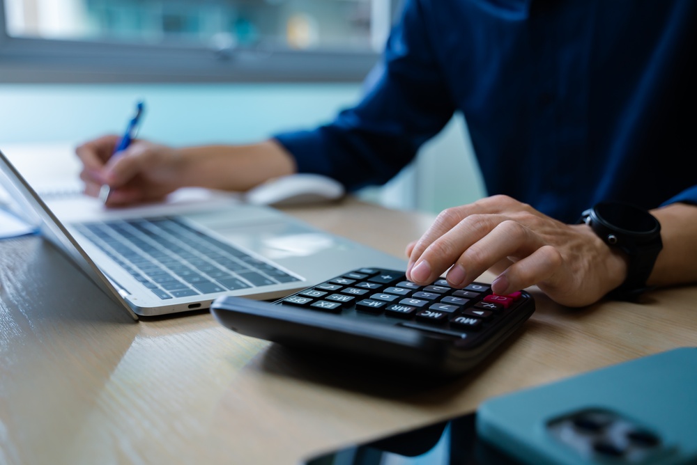 businessman using calculator and smartphone beside laptop