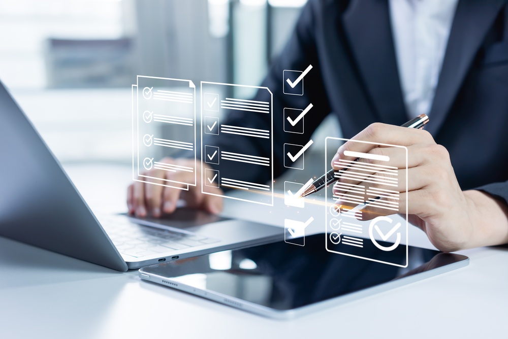 Businessman uses a tablet and laptop to fill out an online survey and digital form checklist